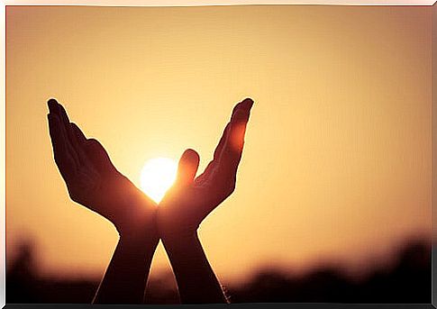 Open hands holding the sun at sunset