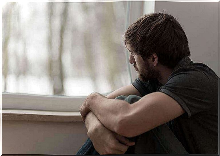 Man looking out a window feeling strange emotions