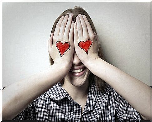 Woman covering her eyes with hearts drawn on her hands