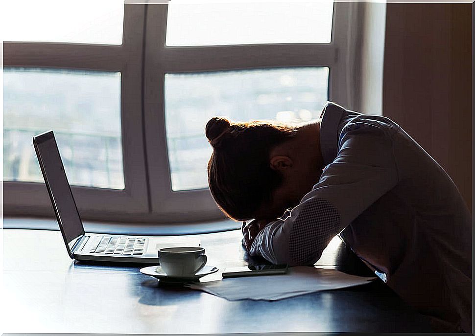 Woman with forehead resting on sad table