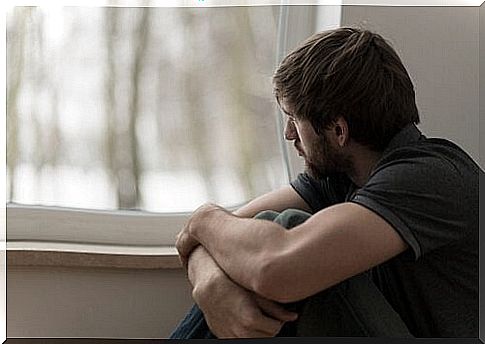 Sad man looking out the window thinking about his problems to express feelings