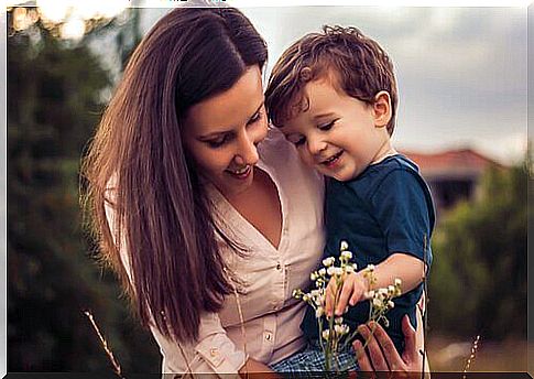 Mother with her child in her arms looking at a flower