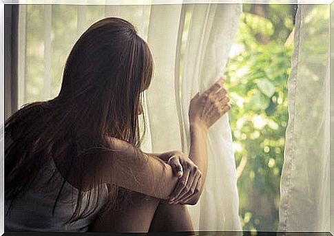 Sad woman thinking about her life looking out the window