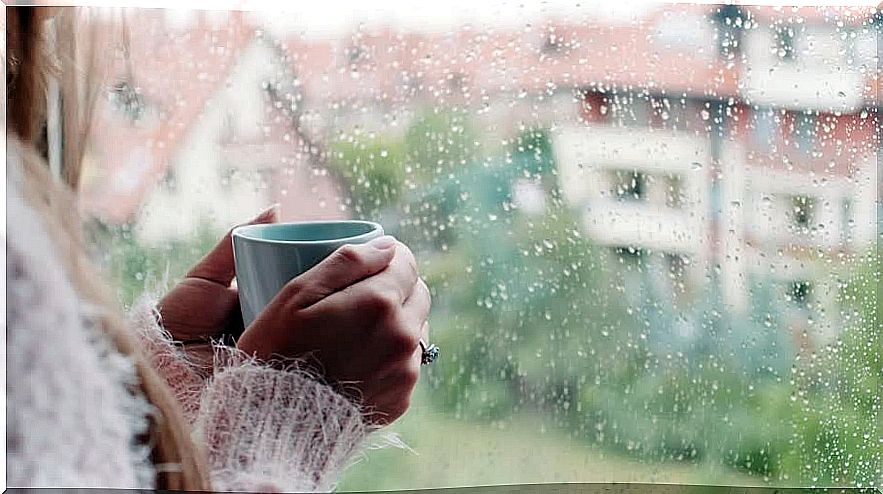 woman with cup of tea listening to the sound of rain